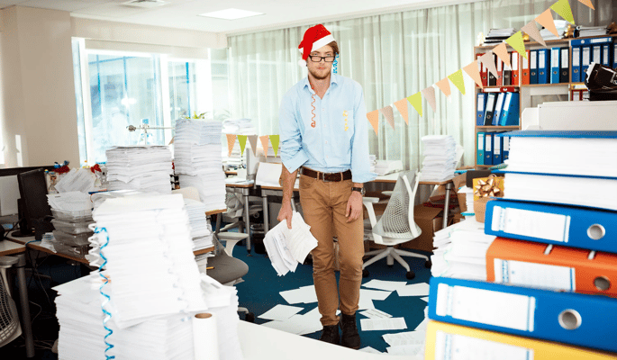 A frustrated young man in an office among piles of papers